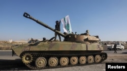 Бунтовнички борец стои над воено возило додека носи знаме на Хајат Тахрир ал-Шам во градот Сараќеб во северозападната провинција Идлиб, 1 декември 2024 година