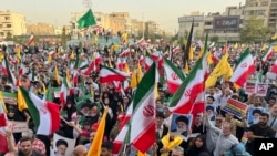 Protestors carry Iranian flags and posters of Supreme Leader Ayatollah Ali Khamenei while chanting anti-US and Israel slogans in Tehran on June 24