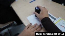 Një zyrtare e Komisionit Zgjedhor duke vulosur votën e një qytetari në një qendër votimi në Prishtinë.