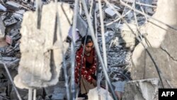 Një vajzë duke shpëtuar sende nga rrënojat e një ndërtese të shembur në Gazë, më 24 prill 2024.