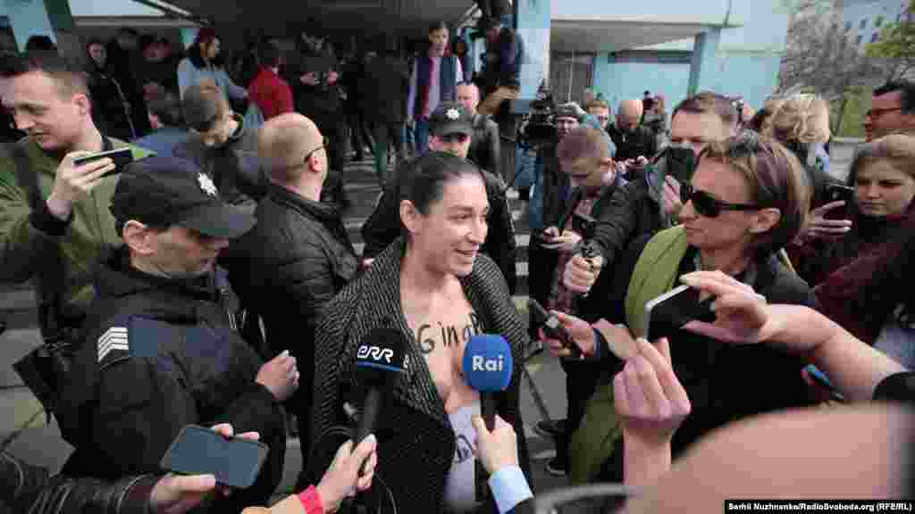 Yuliya adlı faalci saylav bölüginiñ yanına çıplaq köküsnen keldi, onıñ üstünde "pig in a poke" yazısı bar edi. &nbsp;