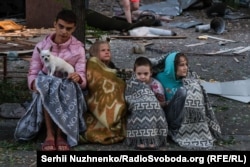 Patru copii stau ghemuiți, împreună cu câinele lor, pe marginea străzii în urma atacului rusesc asupra Kievului din noaptea de miercuri spre joi, 28 august 2025.