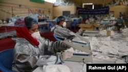 آرشیف- کارگران در حال دوخت ماسک صورت در یک کارخانه در کابل