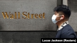 Un bărbat cu mască trece pe Wall Street, în timp ce pandemia de coronavirus a cuprins New York-ul
