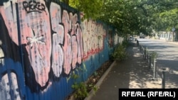 Terenul viran de pe Calea Victoriei este inconjurat cu gard de metal, spart din loc în loc.