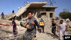 یک مرد در حال انتقال یک طفل مجروح در ولایت ادلب سوریه