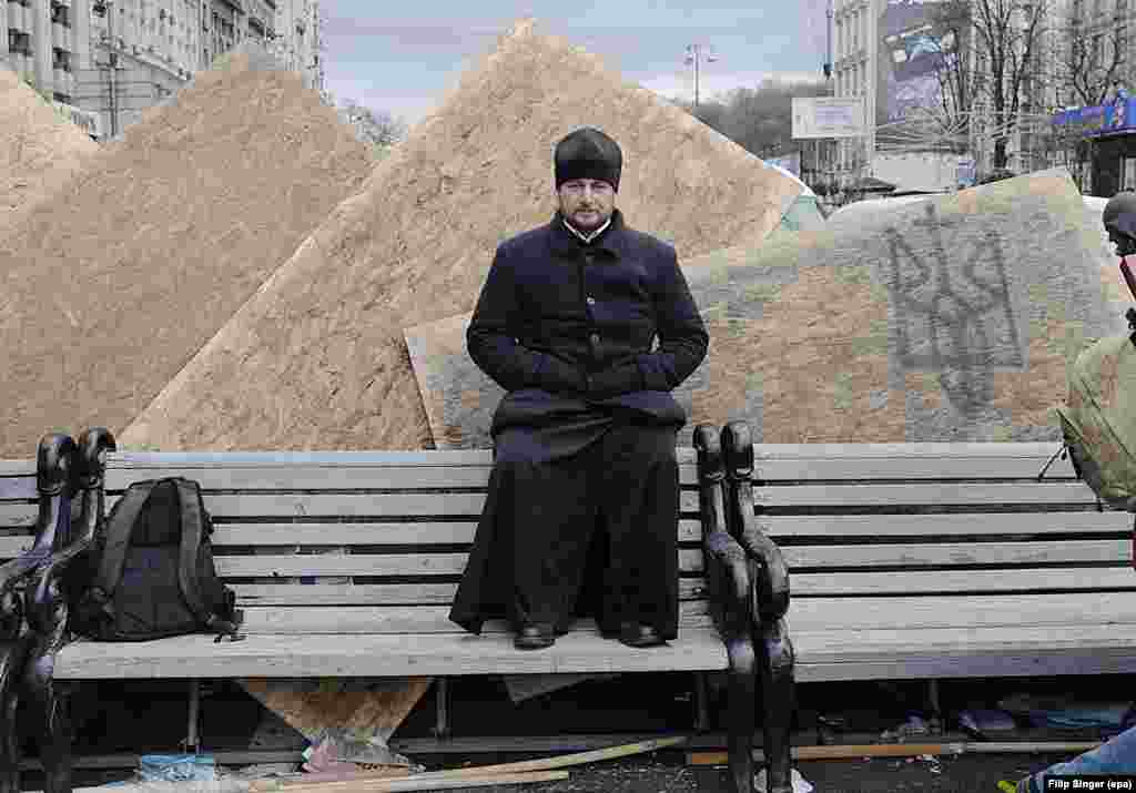 An Orthodox priest sits on a bench at Kyiv's Independence Square.