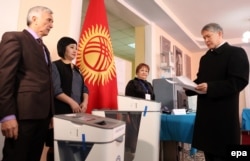 Kyrgyz President Almazbek Atambaev (right) arrives to cast his ballot at a polling station during the referendum on constitutional changes in Bishkek on December 11.