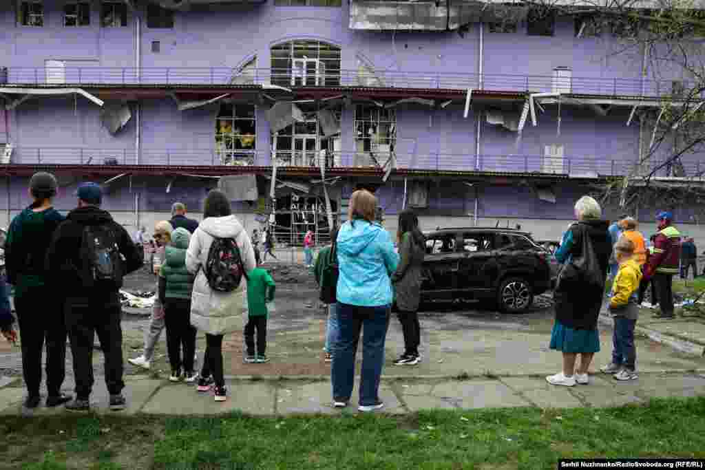 Жители Оболонского района Киева смотрят на поврежденное российским ударом здание 
