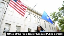 Presidentja e Kosovës, Vjosa Osmani, e fotografuar pranë flamurit amerikan dhe atij të Kosovës në SHBA. 
