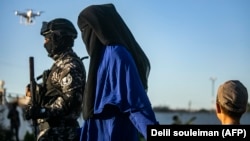 Күрд козголоңчуга туткунга түшүп берген аял баласы менен. Сирия. 