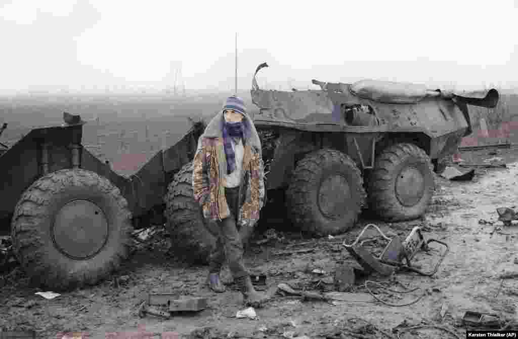 Čečen gleda prema ruskom kontrolnom punktu dok stoji ispred olupine ruskog oklopnog transportera koji je uništen u sukobu između čečenskih pobunjenika i ruskih trupa u selu 40 kilometara zapadno od Groznog 31. januara 1995.