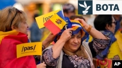 Një grua mban flamurin moldavian dhe atë të BE-së gjatë një tubimi pro-BE të partisë në pushtet, PAS, në Kishinjev, Moldavi, 26 shtator 2025, para zgjedhjeve parlamentare të 28 shtatorit.