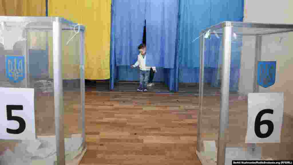 A child waits for his parents to cast their ballots at a polling station in Kyiv during the second round of Ukraine's presidential election on April 21.