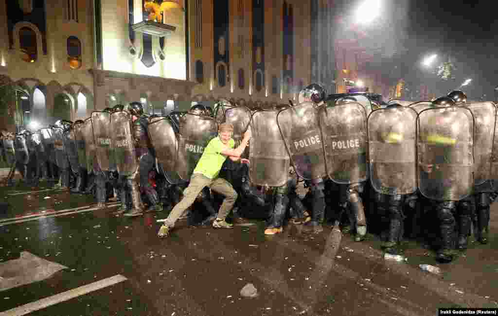 A protester pushes into police lines. In a video shared by former Georgian President Mikheil Saakashvili, a protester appears to be hit by a projectile as he remonstrates with police lines in front of the parliament.&nbsp;