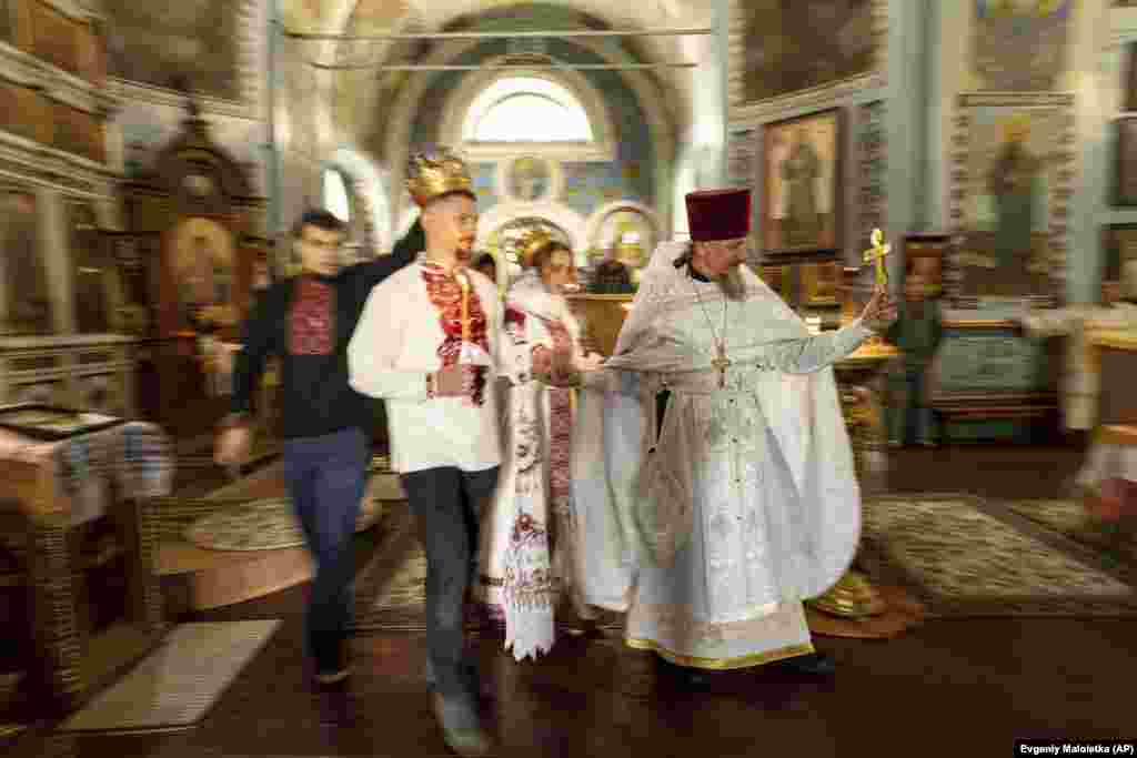 Militarul ucrainean &bdquo;Karp&rdquo; și soția sa, Anna, o voluntară, sunt conduși de un preot în timpul ceremoniei de căsătorie din regiunea Harkov, la 24 iulie. Creșterea masivă a numărului de nunți în Ucraina are un precedent istoric. La apogeul celui de-al Doilea Război Mondial, în 1942, în Statele Unite au avut loc 1,8 milioane de nunți în 12 luni - o creștere de 83% față de deceniul anterior.
