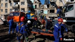 Echipele de salvatori intervin la o clădire care a fost lovită de una dintre bombele rusești. 