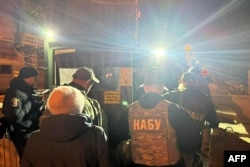 Ofițeri de la Biroul Național Anticorupție din Ucraina trec printr-un punct de control în districtul guvernamental din Kiev, în timp ce efectuează o razie la biroul lui Andri Iermak, în dimineața zilei de 28 noiembrie.