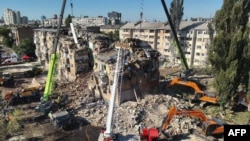 Rescuers conduct a search and rescue operation in and around a residential building heavily damaged during a large-scale Russian attack on Kyiv on August 28.