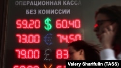 People walk past a screen displaying foreign currency exchange rates outside a bureau de change in Moscow. (file photo)