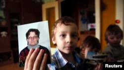 Artur, son of Svetlana Davydova, holds up a photo of his mother at the family's home in Vyazma.