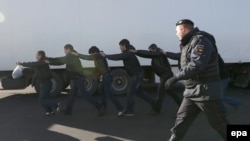 Полицейский сопровождает задержанных мигрантов  в Москве. Иллюстративное фото.