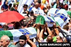 Disa persona bartin 33 trupat e identifikuar të Masakrës së Srebrenicës. Ata u varrosën në kompkeskin memorial në Potoçari. Bosnjë, 11 korrik, 2019.