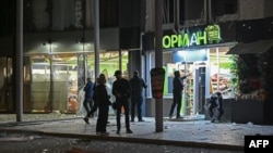 Орус армиясынын чабуулунан талкаланган соода борборунун алдында турган жергиликтүү тургундар. 29-март, 2025-жыл. Харьков.