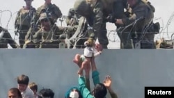 Оогандык качкындар ымыркайын америкалык аскерлерге эвакуация үчүн берип жатат. Кабул. Август, 2021-жыл.