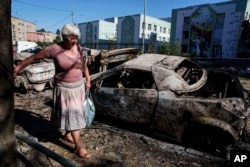 O femeie trece pe lângă mașini distruse de atacul aerian rusesc de la Kiev, la 4 iulie 2025.