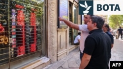 Iranianët duke shikuar kurset e këmbimit të valutave të huaja në sheshin Ferdovsi në kryeqytetin iranian, Teheran.