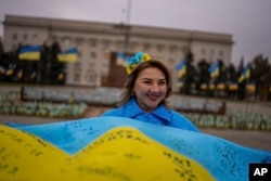 O locuitoare a Hersonului, ținând un steag al Ucrainei semnat de soldați, pe 11 noiembrie 2024, când orașul sărbătorește împlinirea a doi ani de la eliberarea de sub ocupația rusă.