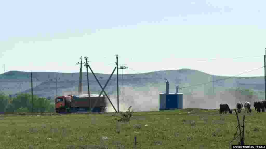 Селищною дорогою їдуть самоскиди, що перевозять чорнозем і пісок з кар'єру на околиці Зуї