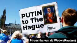 გაეროს საერთაშორისო სასამართლოს შენობის წინ გამართული საპროტესტო აქციის მონაწილეები რუსეთის პრეზიდენტის, ვლადიმირ პუტინის დაპატიმრებას მოითხოვენ. ჰააგა, ნიდერლანდი. 2024 წლის 7 მაისი