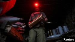 Un soldat din Brigada 141 Mecanizată Separată a Ucrainei poartă muniție pentru un obuzier autopropulsat 2S1 Gvozdika în timp ce îl pregătește să tragă asupra trupelor rusești din regiunea Donețk, pe 3 septembrie.