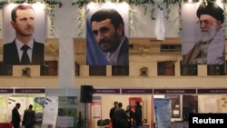 تصاویر علی خامنه‌ای (راست) رهبر جمهوری اسلامی، محمود احمدی‌‌نژاد، رئیس‌جمهور سابق ایران، و بشار اسد، رئیس‌جمهور مخلوع سوریه، در نمایشگاهی در تهران