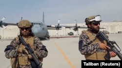 Членовите на воената единица Бадри 313 чуваат стража додека талибанскиот портпарол Забихула Муџахид ги изнесува своите забелешки на аеродромот во Кабул, 31 август 2021 година