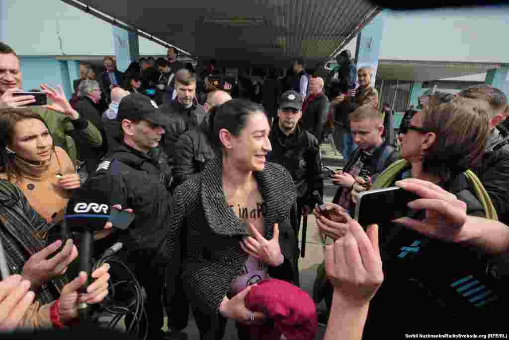 A Femen activist protests outside a polling station where Volodymyr Zelenskiy voted in Kyiv. The woman&nbsp;warned voters that a Zelenskiy presidency could end up being a "funny mistake."