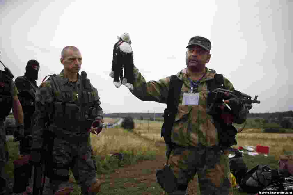 A pro-Russian separatist holds a child's stuffed toy found at one of the crash sites.