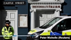 A police officer stands outside Zizzi's restaurant in Salisbury where Sergei Skripal and his daughter Yulia are known to have visited shortly before they were found poisoned in the center of the town. 