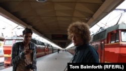 Blogger and activist Ilya Varlamov (right, with camera) working on his civil activism campaign on a Moscow train platform with a fellow activist.