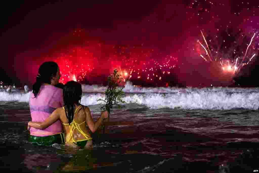 Люди наблюдают за традиционным новогодним фейерверком с воды на пляже Копакабана в Рио-де-Жанейро, Бразилия.