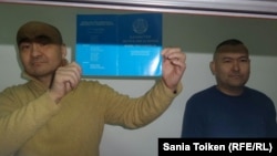 Макс Бокаев показывает Конституцию Казахстана в суде, где судят его и Талгата Аяна (справа). Атырау, 18 октября 2016 года.