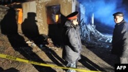 Полицейские у разрушенного дома на месте спецоперации против подозреваемых боевиков-исламистов в поселке Арашан вблизи Бишкека. 5 января 2011 года.