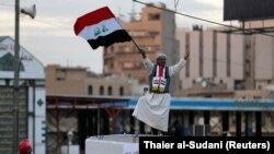 Майрамдык салтанат учурунда Багдаддагы Тахрир аянтында Ирактын желегин кармап турган адам. 10-декабрь, 2017-жыл.