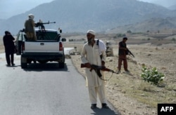 Afghan Local Police keep watch along the road near a checkpoint in Achin