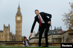 Дүйнөдөгү бою эң кыска адам Гандра Бахадур Данги эң бийик адам Султан Кузен менен рекорддордун Гинесс китебине катталган соң саламдашышууда. Лондон, 13-ноябрь 2014.