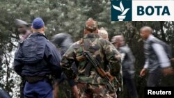 Një zyrtar policor dhe një ushtar duke i vëzhguar migrantët teksa kanë kaluar nga Serbia në një qendër për migrantë në Hungari. Fotografi e 11 shtatorit 2015.