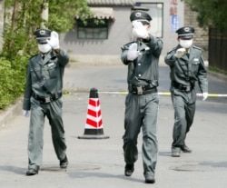 Personeli i sigurisë tenton të parandalojë fotografimin jashtë një spitali në Pekin, në prill të vitit 2003.