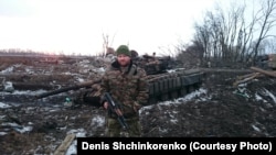 Denis Shchinkorenko stands beside a tank in eastern Ukraine.